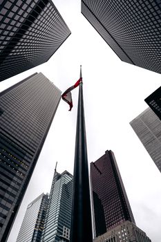 Cityscape with towering skyscrapers converging towards the sky, dominated by a central flagpole.
