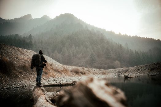 A lone backpacker walking along a serene mountain path with dense forests.