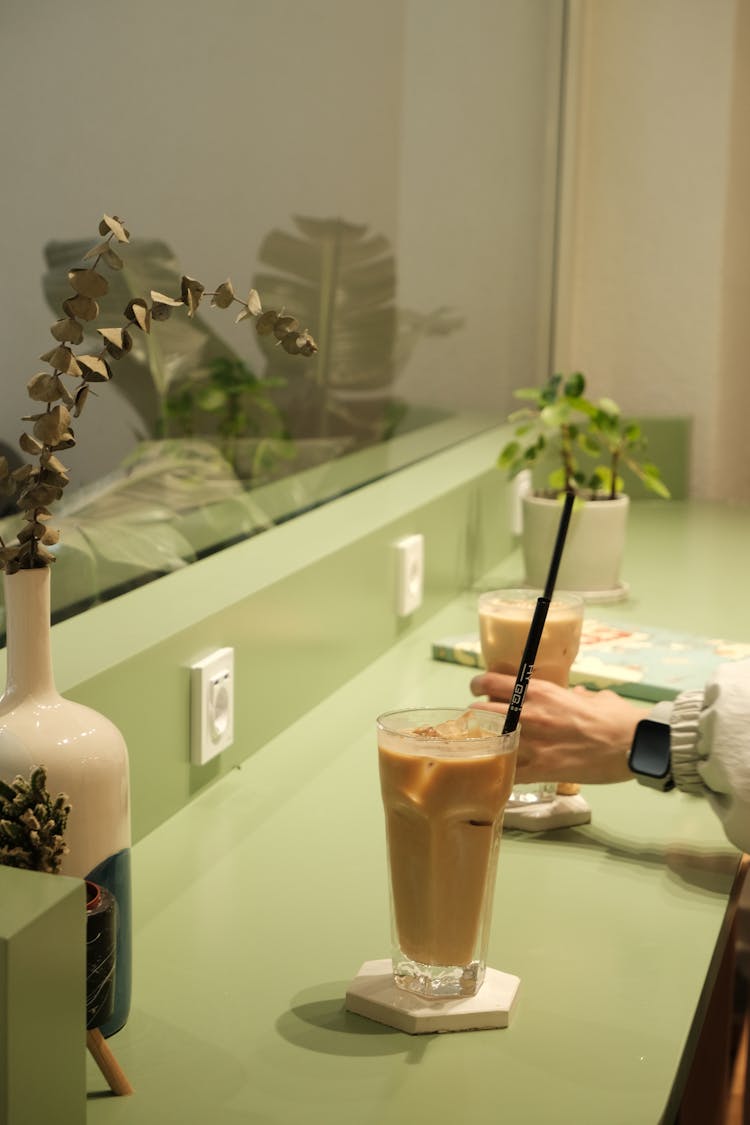 A Person Grabbing A Glass With An Iced Coffee 