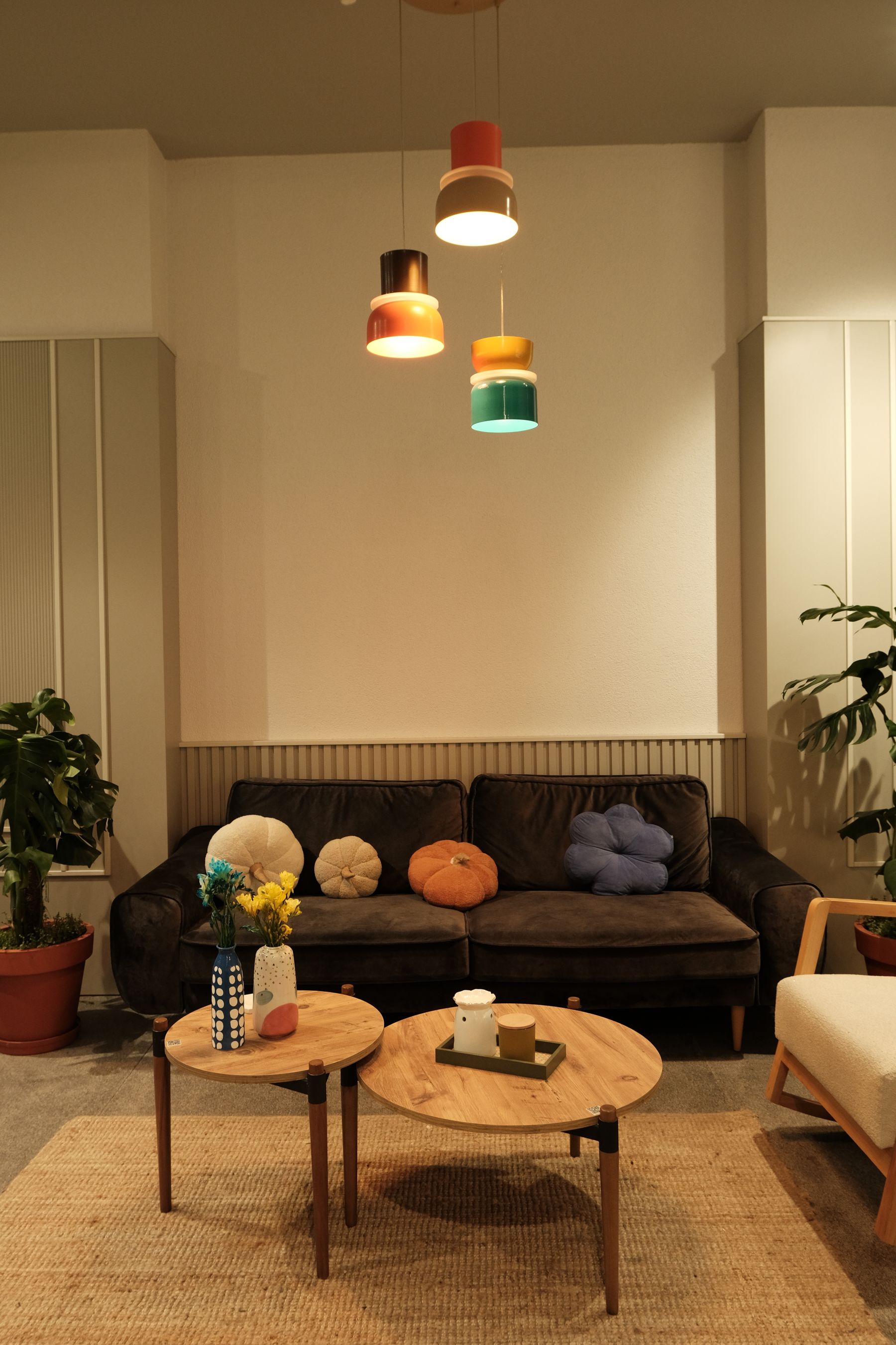 Art Deco living room with fan-pattern ceiling, curved pale seating, dark wood tables, pendant lights and leafy plants