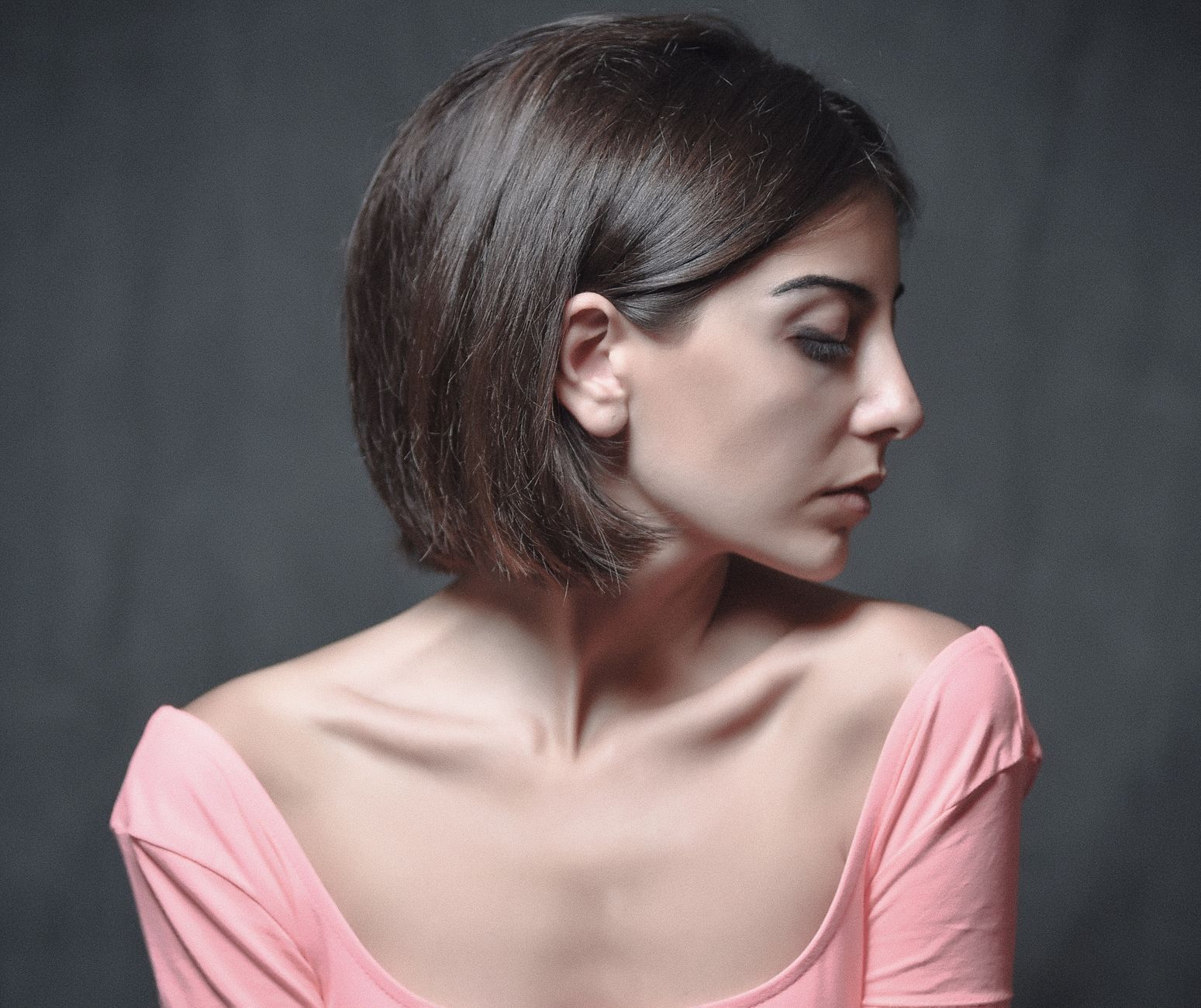 Elegant side profile of a woman with short hair wearing a pink top. Capturing simplicity and beauty.