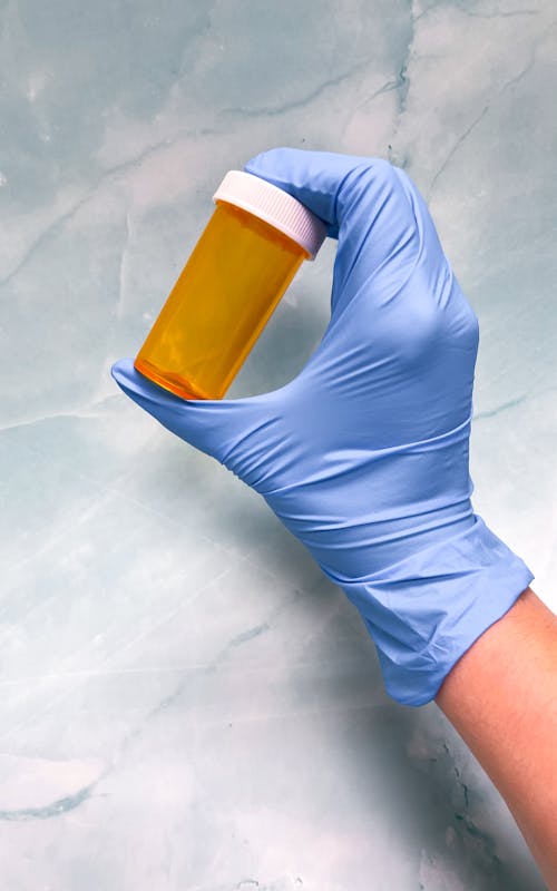 Empty Pill Bottle in Gloved Hand