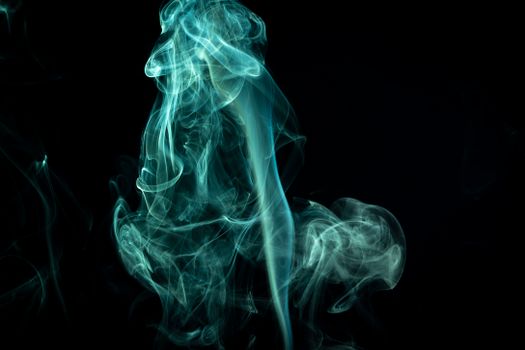 Ethereal blue smoke swirls artistically against a dark backdrop, perfect for design uses.