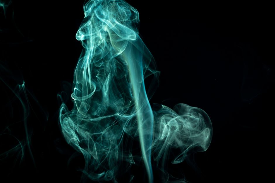 Ethereal blue smoke swirls artistically against a dark backdrop, perfect for design uses.