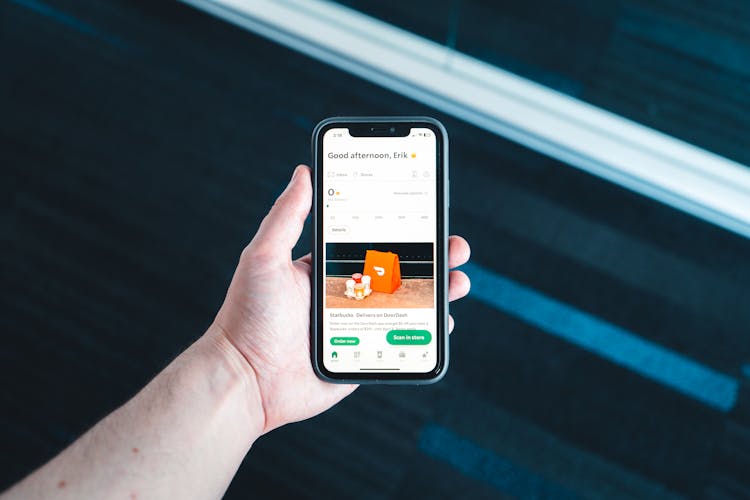 Photo Of A Hand Holding A Smartphone With A Delivery App On Screen