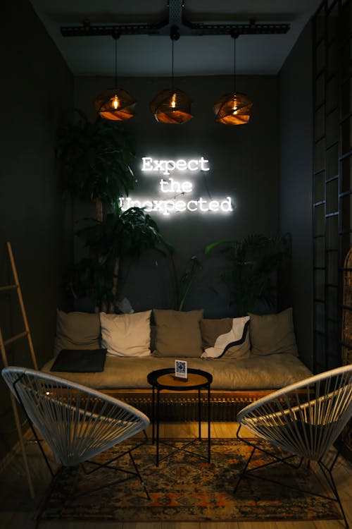 A Neon Sign Hanging on a Wall, above a Sofa in a Cozy Cafe