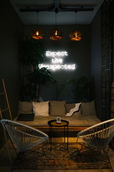 Chic café corner with cozy seating and neon sign art, perfect for relaxation.
