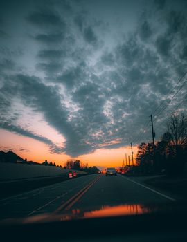 A captivating sunset over Powder Springs, GA road with silhouetted trees and vibrant sky.