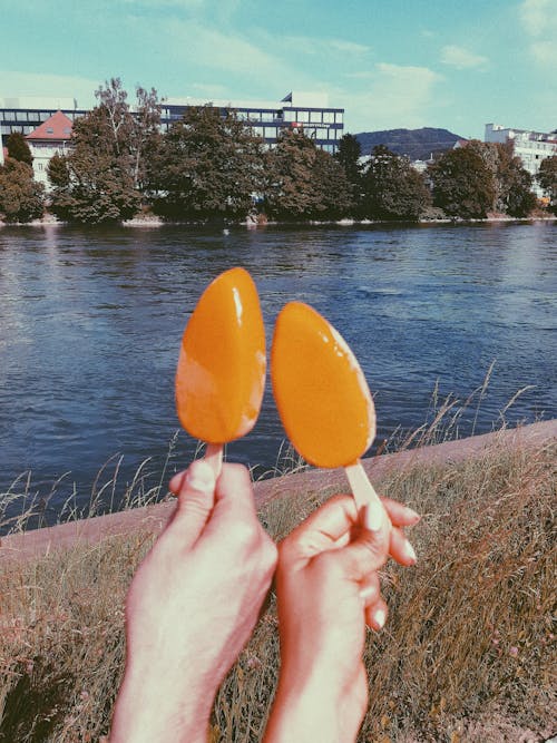 Close-up of People Holding Ice Creams on the Background of a Body of Water 