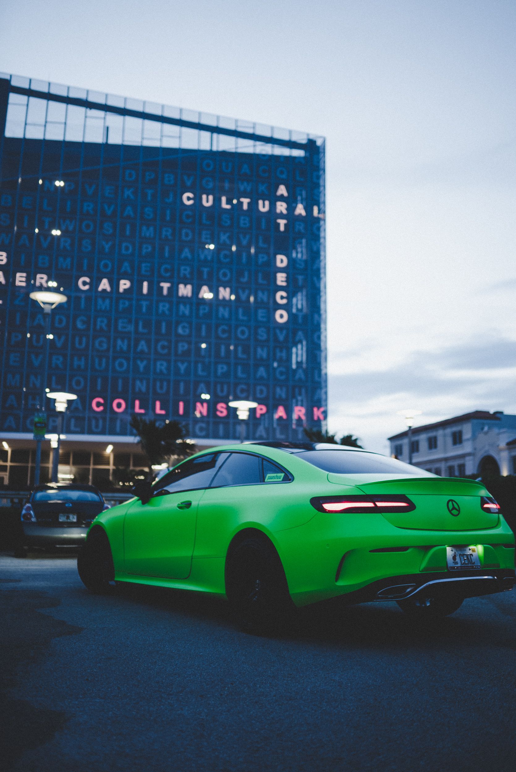 Striking green sports car parked near modern architectural building at twilight.