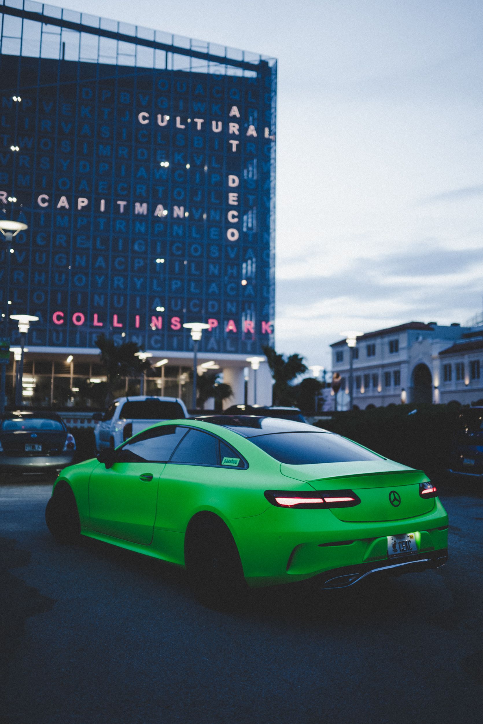 A striking green Mercedes C63 coupe parked near modern architecture at twilight.