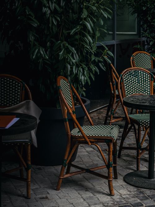 Free A cozy outdoor café setting with vintage wicker chairs and a lush backdrop, perfect for a serene retreat. Stock Photo