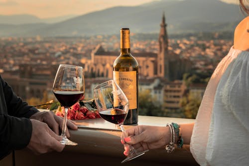 Foto de Stock de Manos de Hombre y Mujer Sosteniendo Copas de Vino en la Ciudad en la Toscana