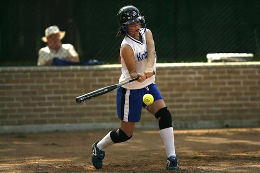 A female athlete concentrating while batting during a softball game outdoors.