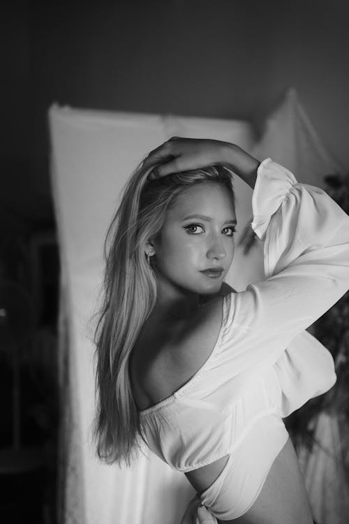 Black and White Photo of a Young Woman Standing with Hands in Hair 