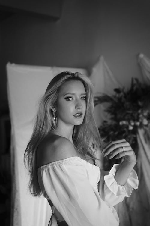 Black and White Photo of a Young Woman in a White Dress Playing with Her Hair 