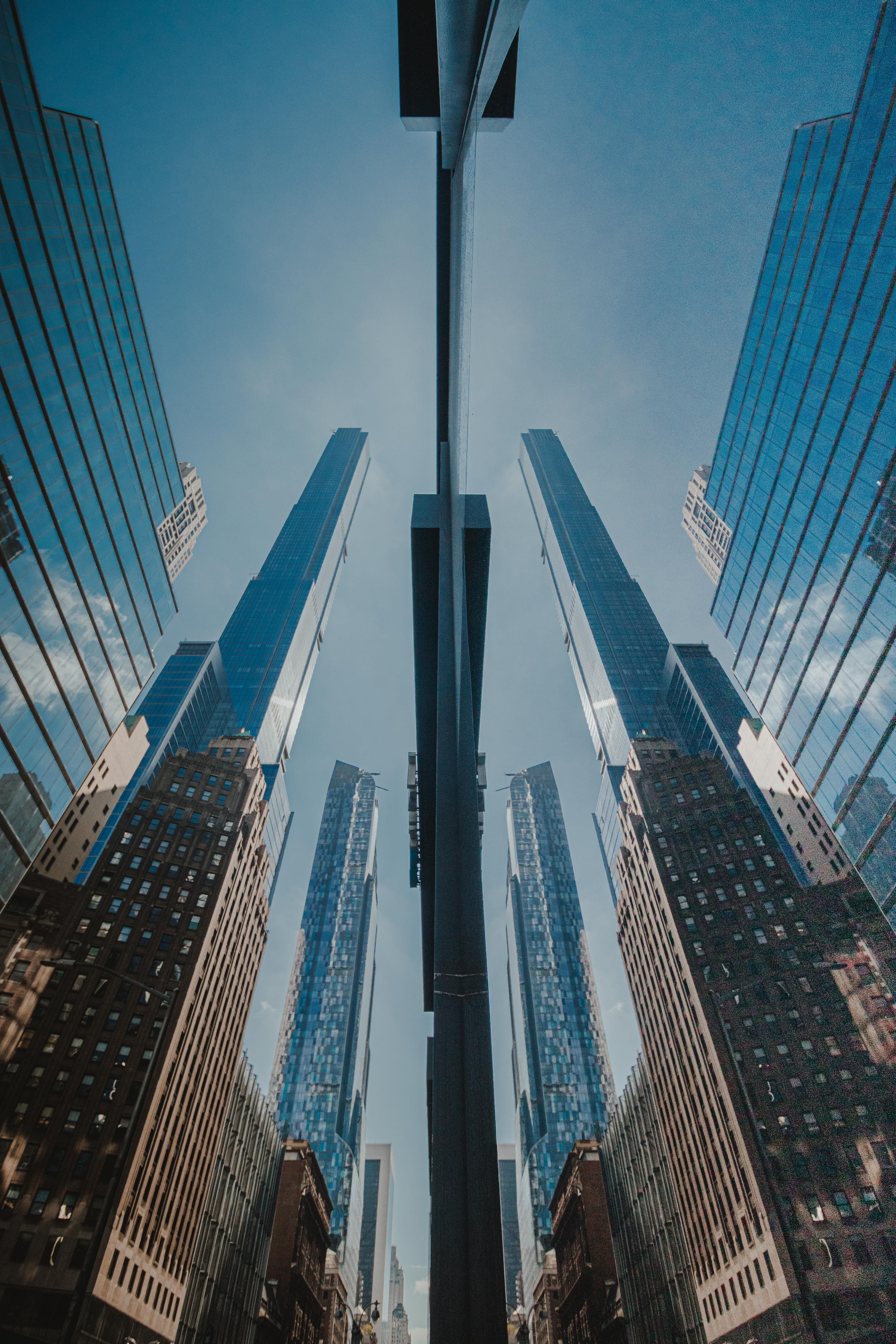 Striking low-angle view of skyscrapers reflecting in glass, showcasing urban architecture.
