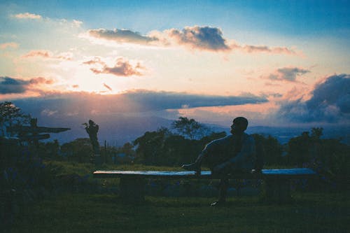 Silhouette of a Man Sitting on a Bench at Sunset