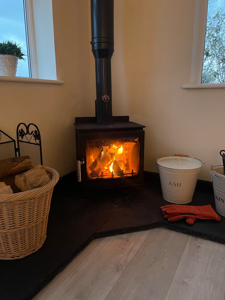 A Wood Burning Stove In A Room With A Basket