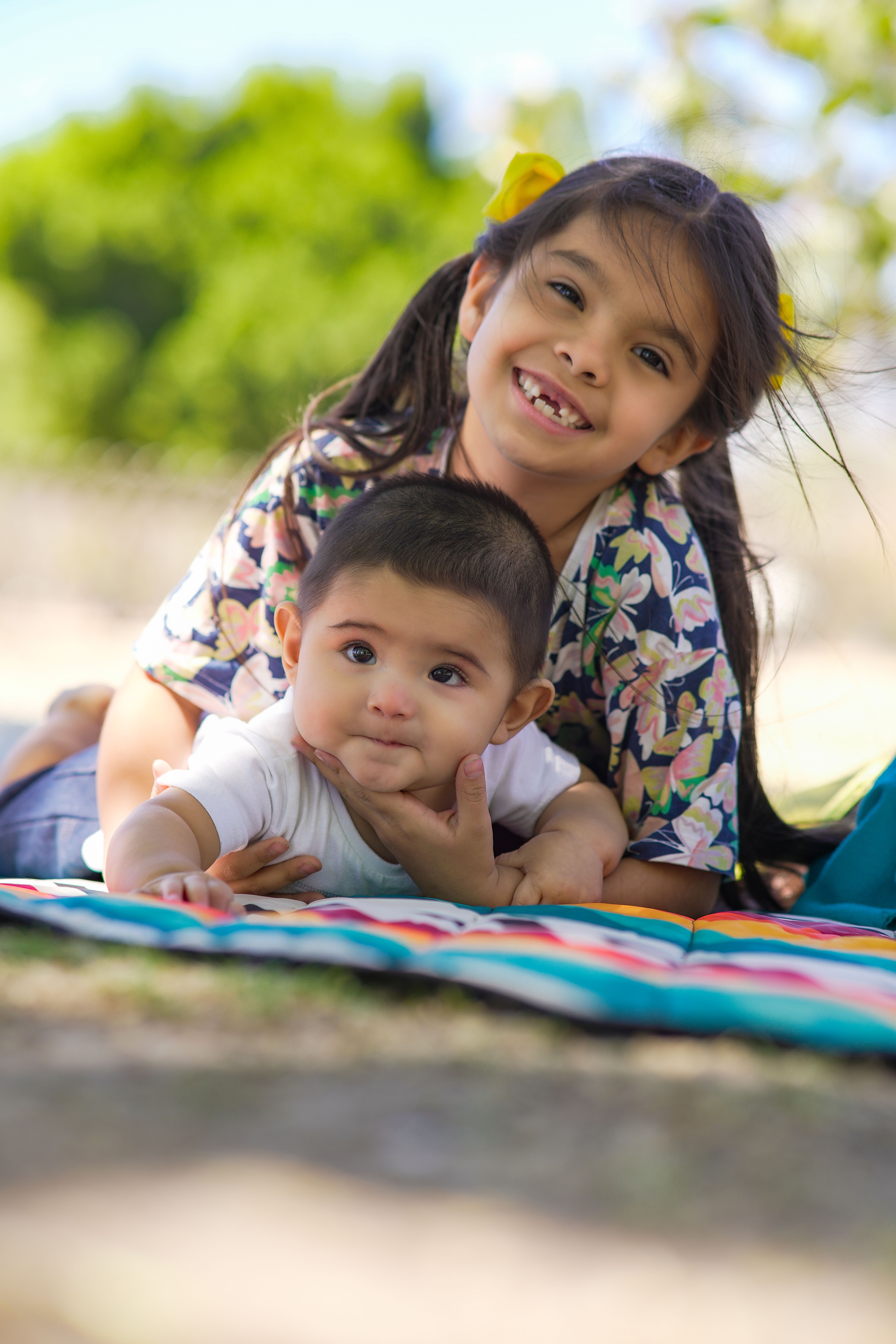 Fotomural Dos hermanos felices tumbados sobre una manta al aire libre, disfrutando de un día soleado.