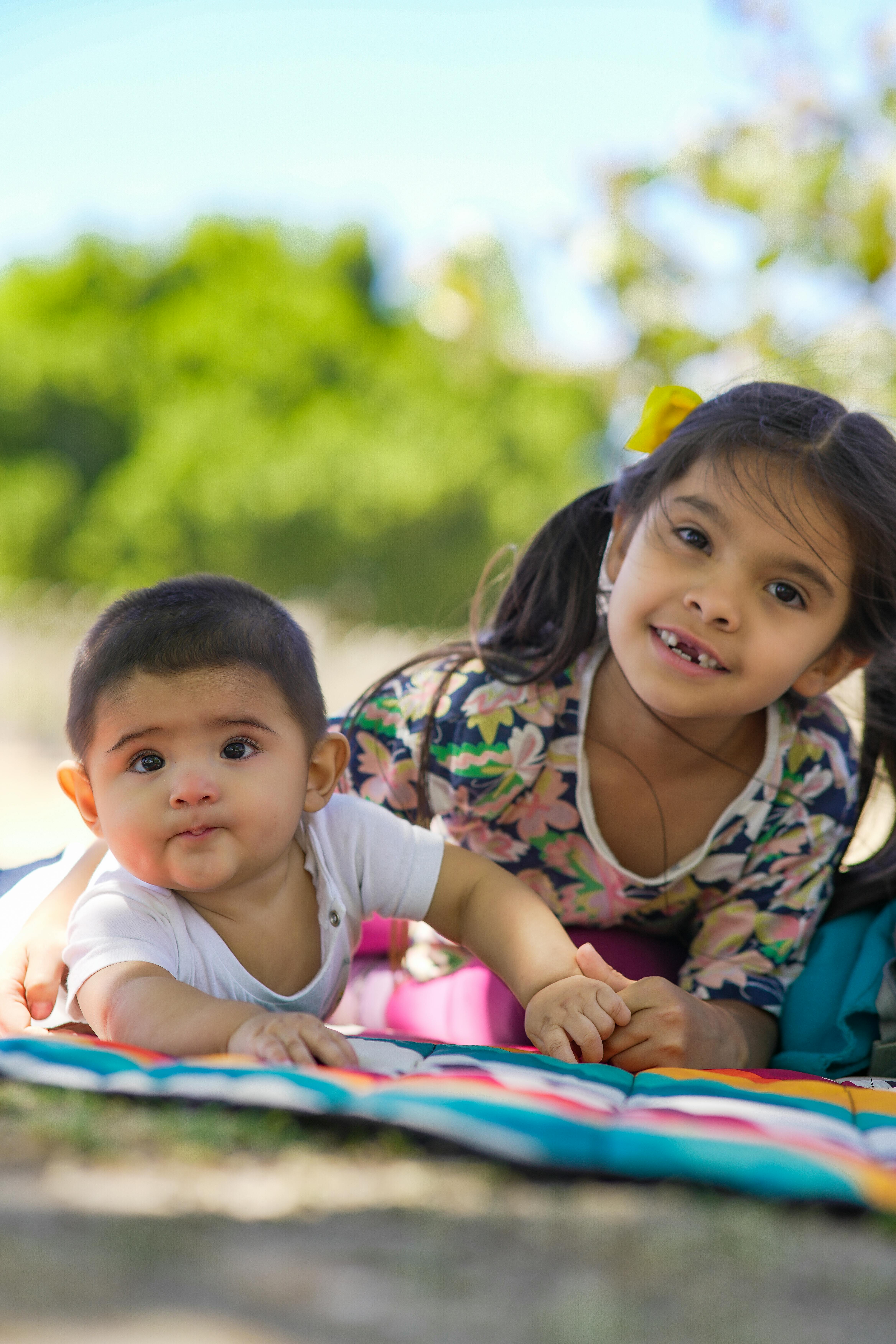 girl and boy lying down on blanket