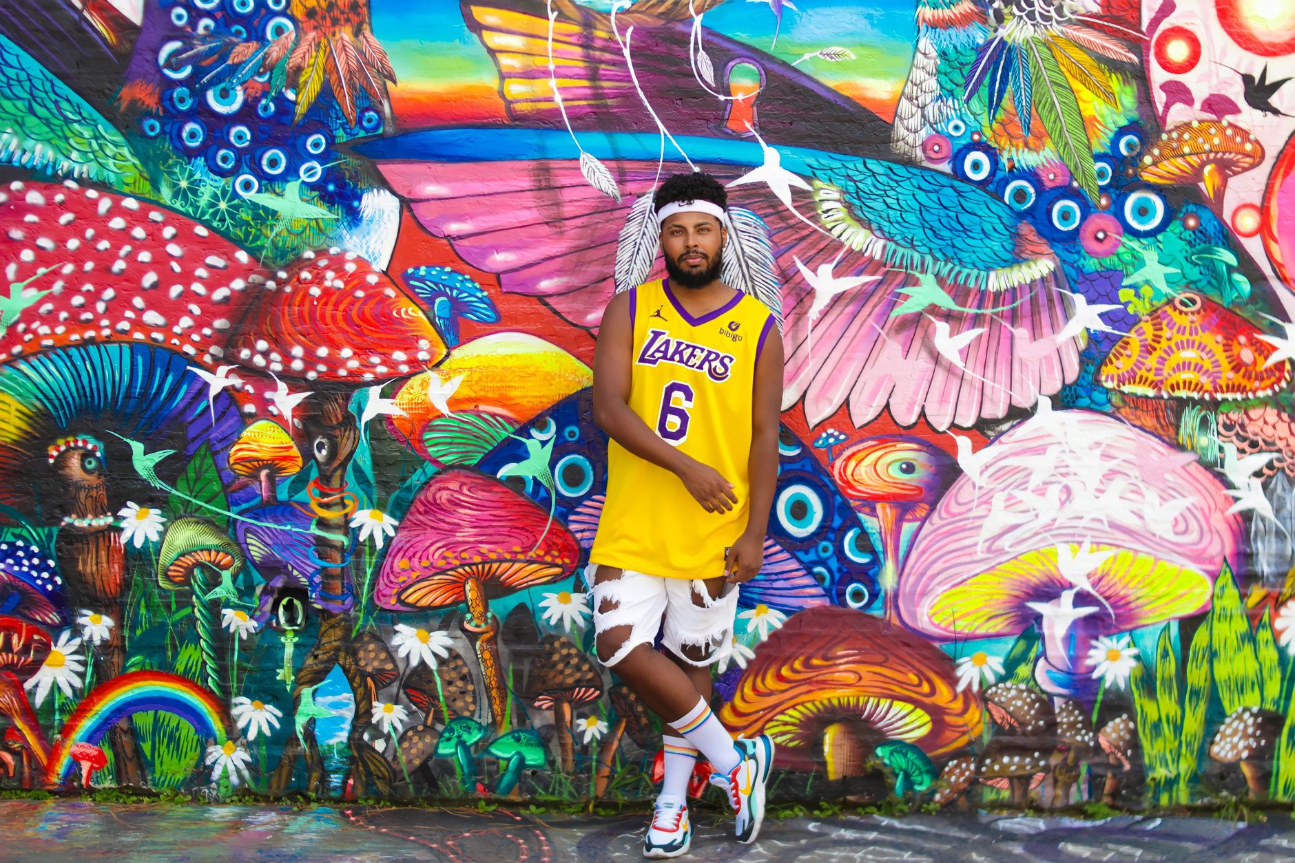 Vibrant street art scene featuring a man in a Lakers jersey posing against a colorful mural in Brazil.