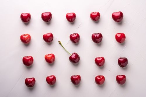 Free Top-down view of fresh cherries arranged in rows on a white background, capturing their natural beauty. Stock Photo