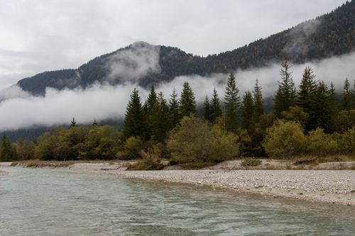 Free Calm river scene with mountains and fog-covered forest, tranquil atmosphere. Stock Photo