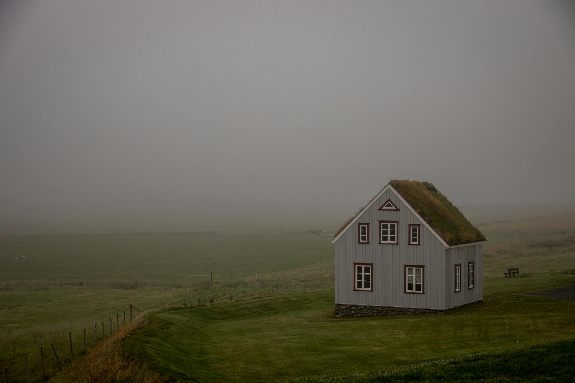 Charming country house with a grass roof amidst a foggy rural landscape.