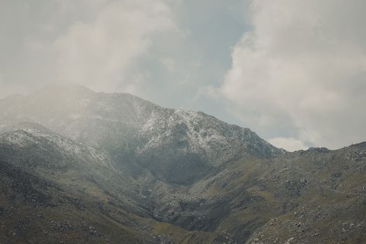 A scenic view of fog-covered mountain peaks under a cloudy sky, captured from a high altitude.