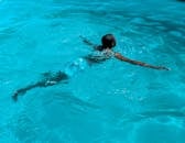 一名男子在清澈的蓝色泳池中游泳，尽显休闲与活力