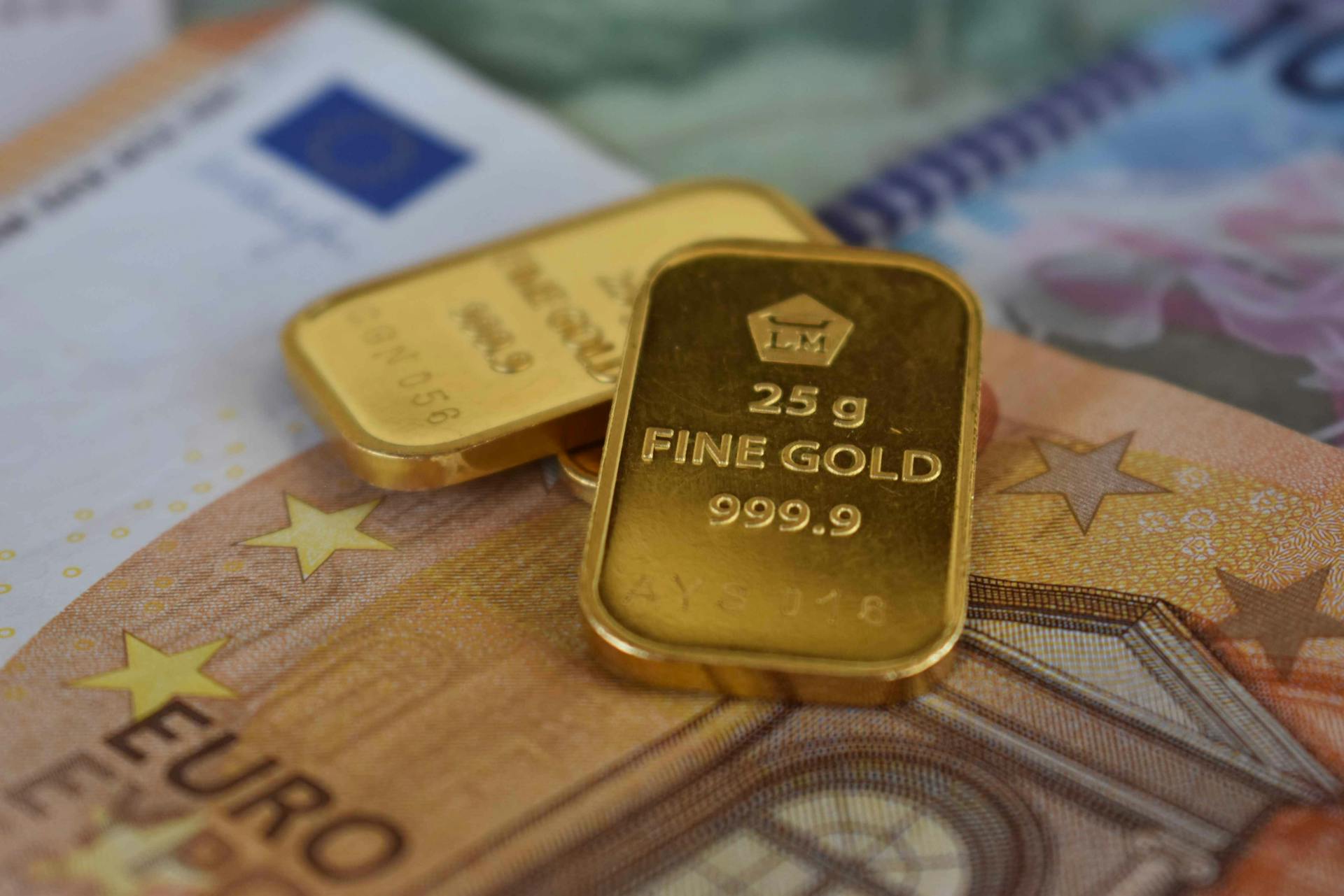 Detailed view of gold bullion bars placed on European currency euro banknotes, symbolizing wealth and investment.