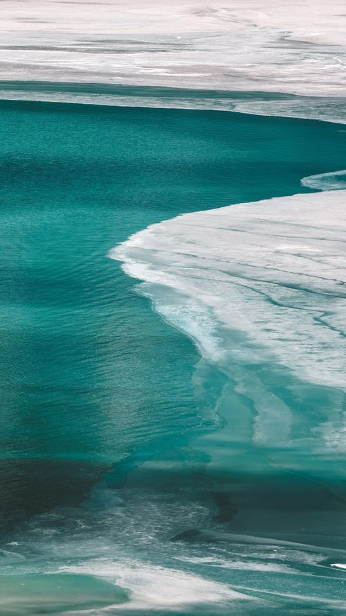 Free Aerial view of turquoise ocean waves with white foam beautifully curving along the coast. Stock Photo