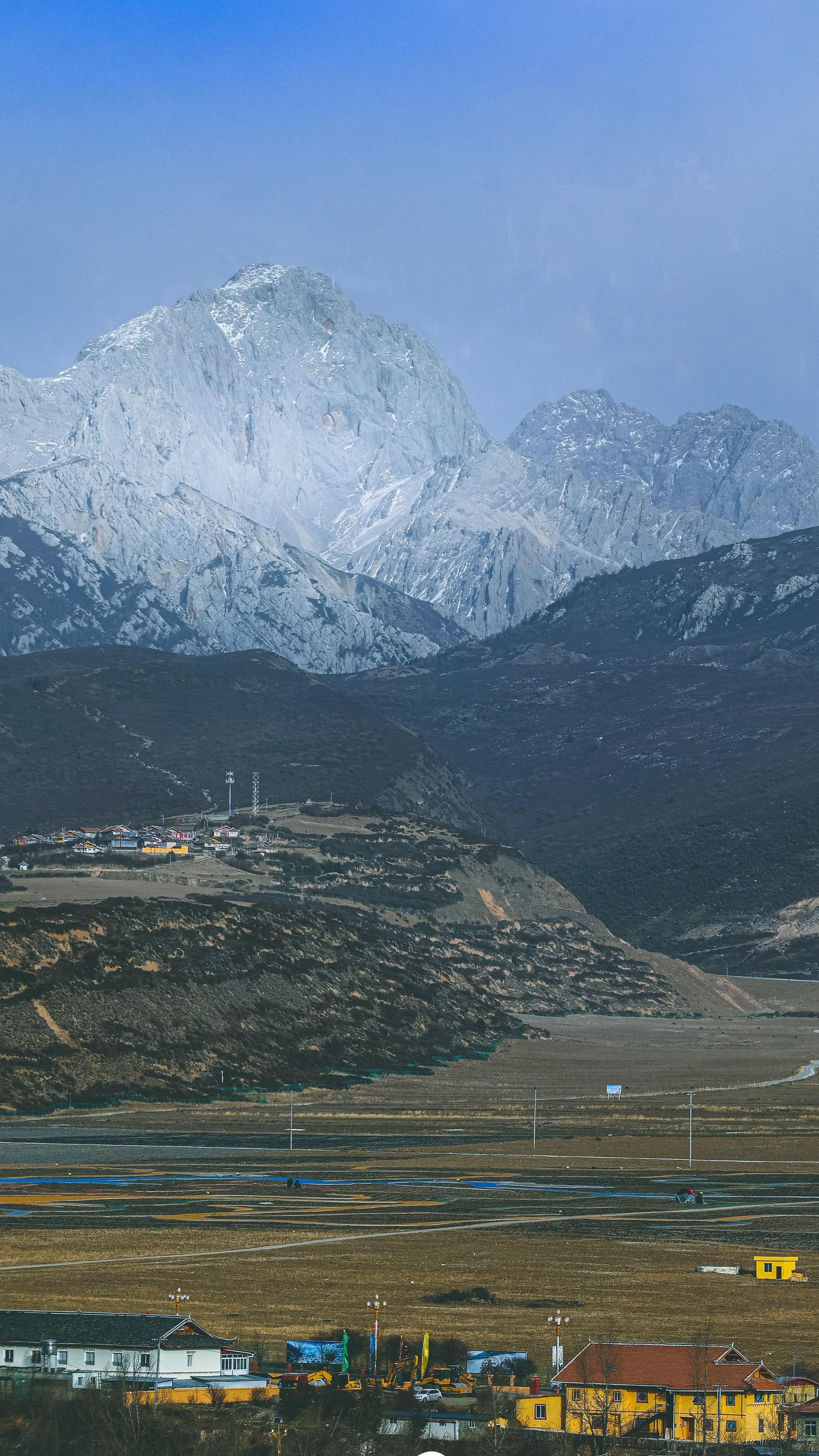 Explore a stunning landscape with majestic snow-capped peaks towering over a serene valley.