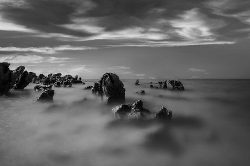 Free Moody black and white seascape featuring foggy rocks and dramatic clouds. Stock Photo