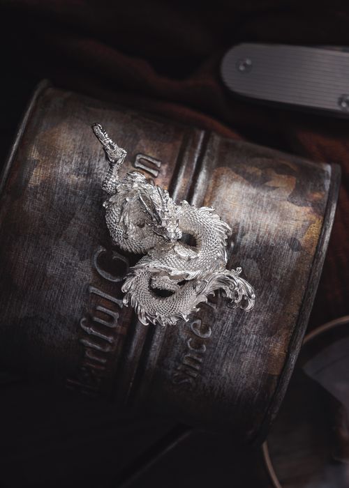 Free A detailed silver dragon necklace elegantly displayed on artistic metallic background. Stock Photo