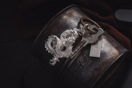 Intricately designed silver dragon keychain placed stylishly on a vintage metal container.
