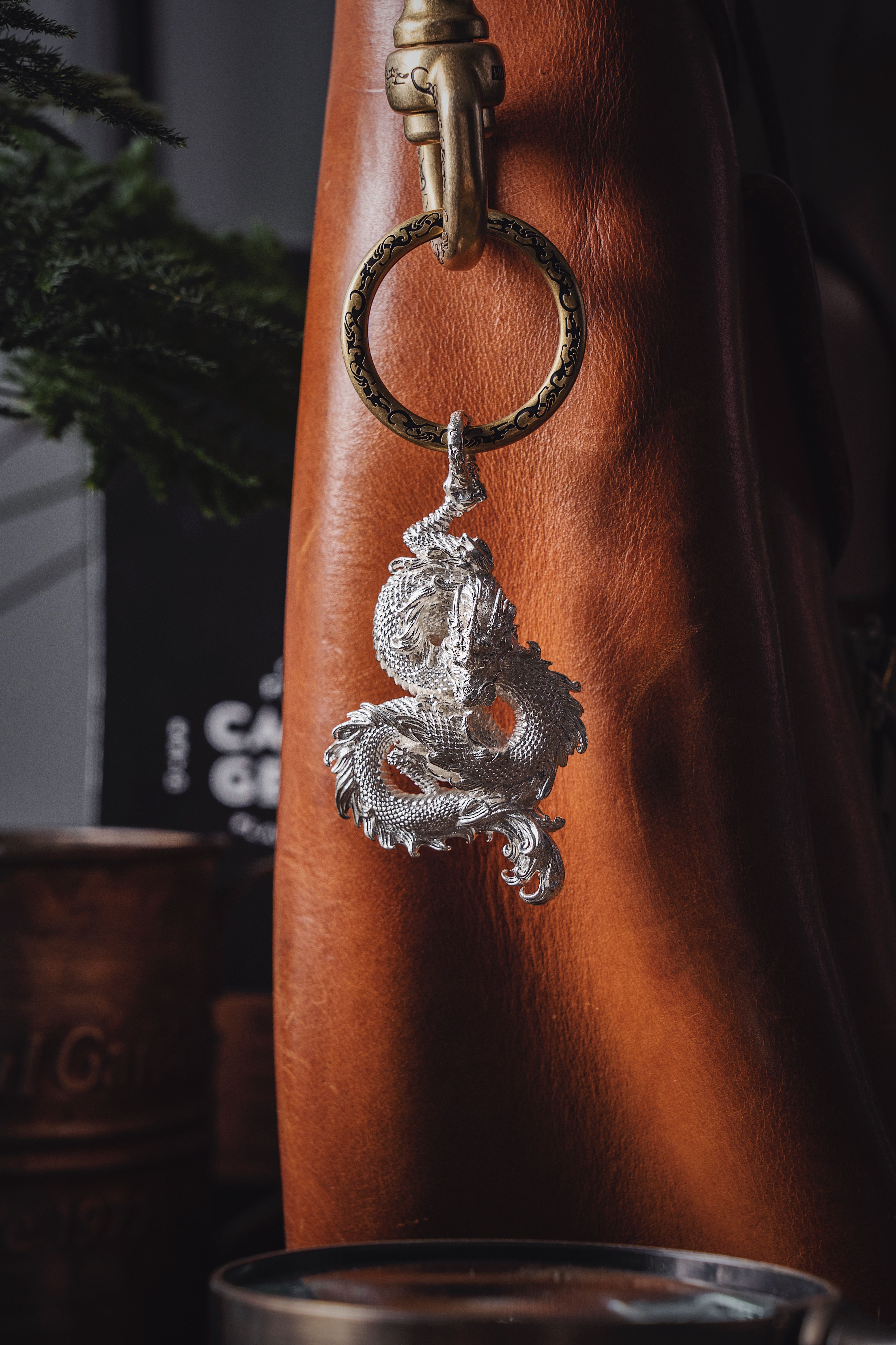 Silver dragon pendant elegantly hanging on a rich leather backdrop, showcasing artistic design.