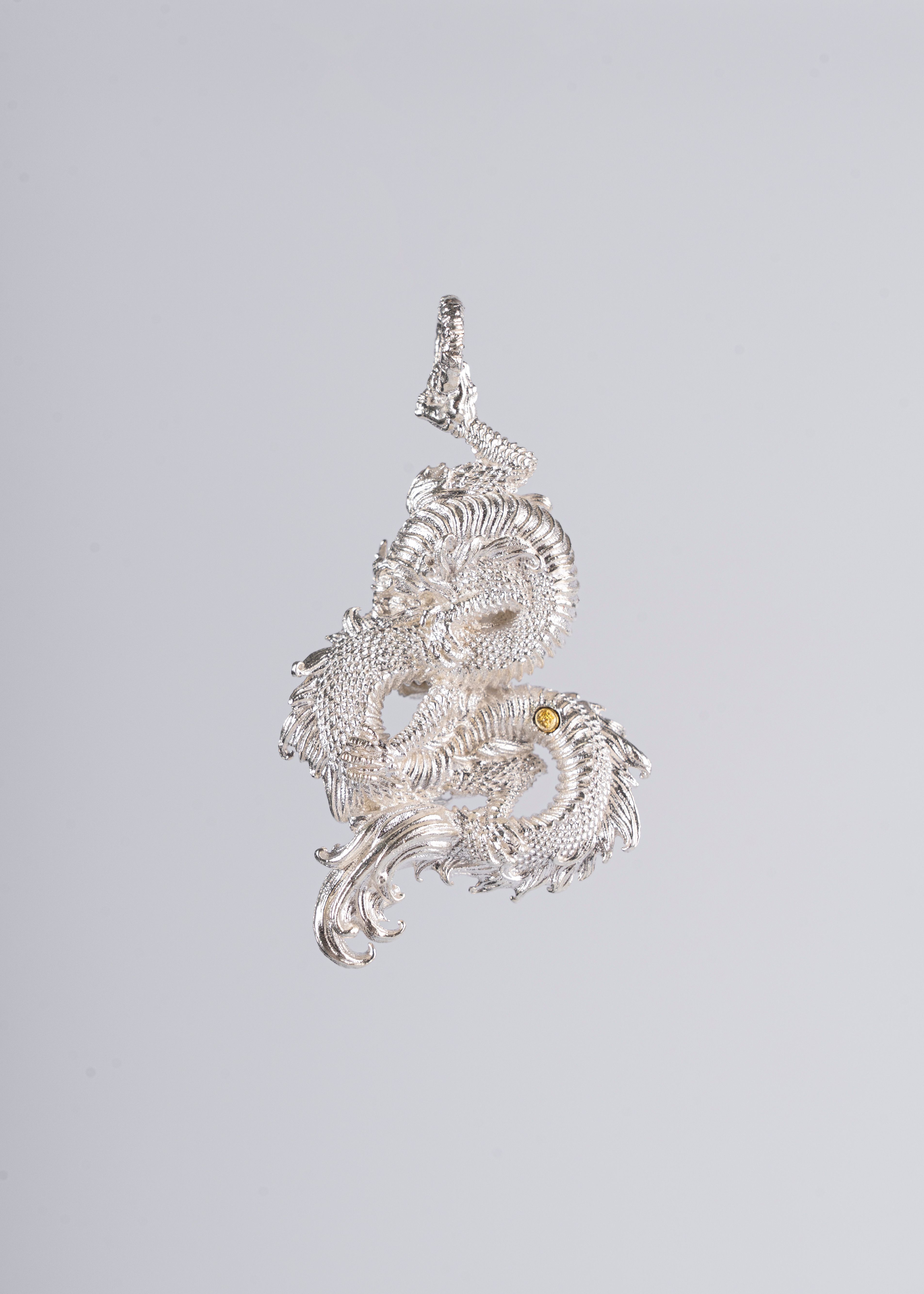 Elegant silver dragon pendant showcasing intricate details on a minimalist background.
