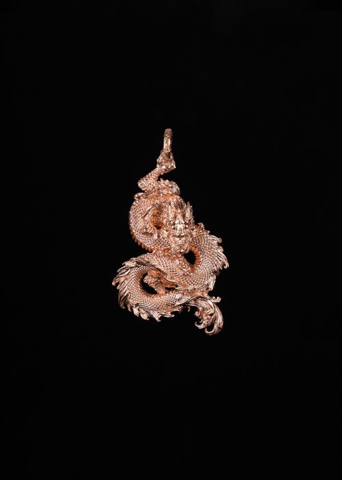 Free A close-up of an intricately designed dragon pendant against a black background. Stock Photo