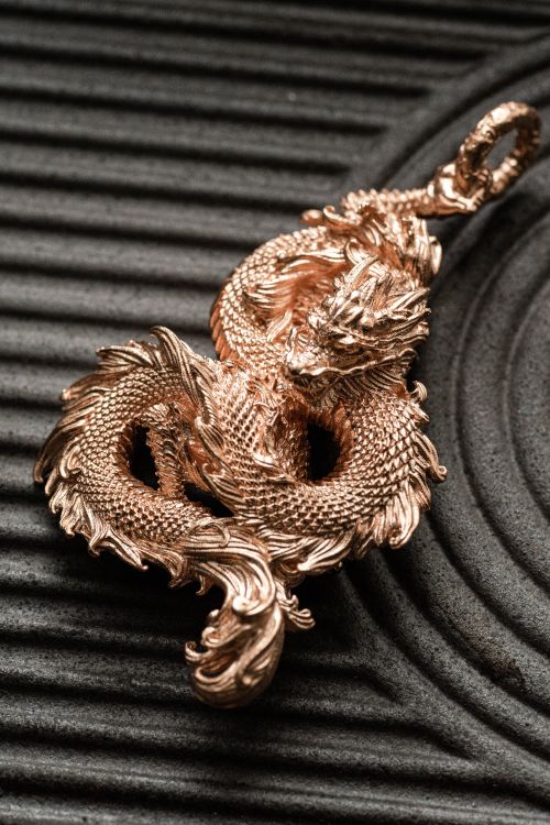 Free Close-up of a detailed golden dragon pendant on textured surface. Stock Photo