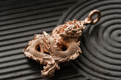 Free Golden dragon pendant with exquisite detailing on textured surface. Stock Photo