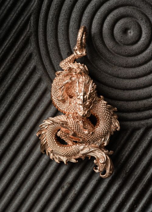 Free Elegant golden dragon pendant with detailed craftsmanship on a textured surface. Stock Photo