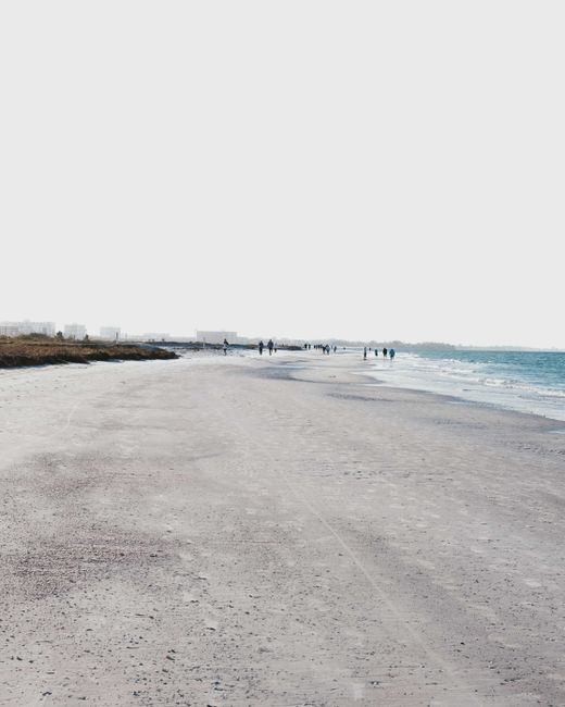 Tranquil beach scene with soft sands and gentle waves under an expansive sky.