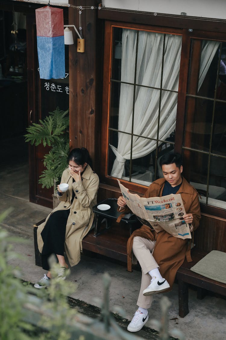 Man Sitting With Woman And Reading Newspaper