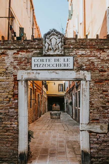 Discover the rustic charm of a historic passage in Venice with a stone arch entrance.