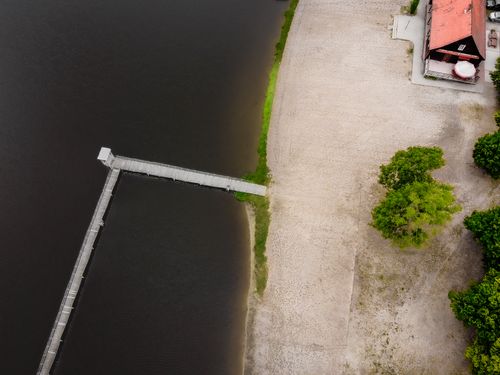 Free A drone shot capturing a peaceful lakeside pier and sandy beach in Zaniemyśl, Poland from above. Stock Photo