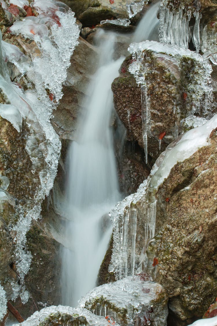 Water Flowing Between Rocks And Hanging Icicles 