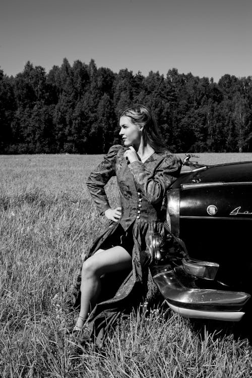Woman in Dress Posing by Car on Meadow