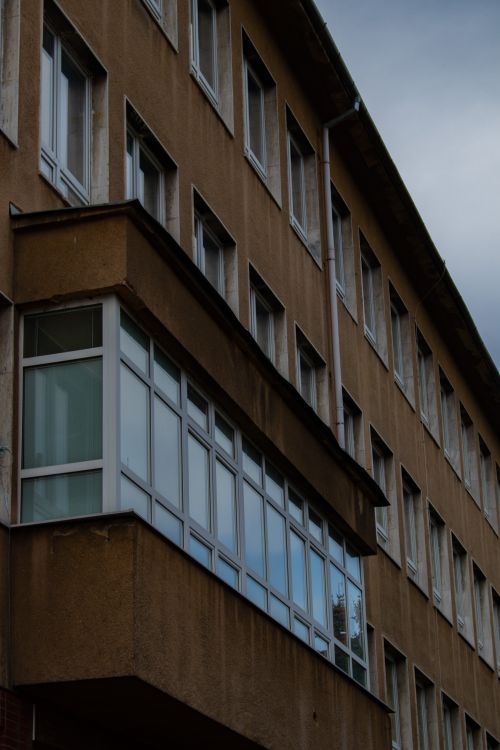 Free An exterior view of a residential building showcasing a row of windows under an overcast sky. Stock Photo